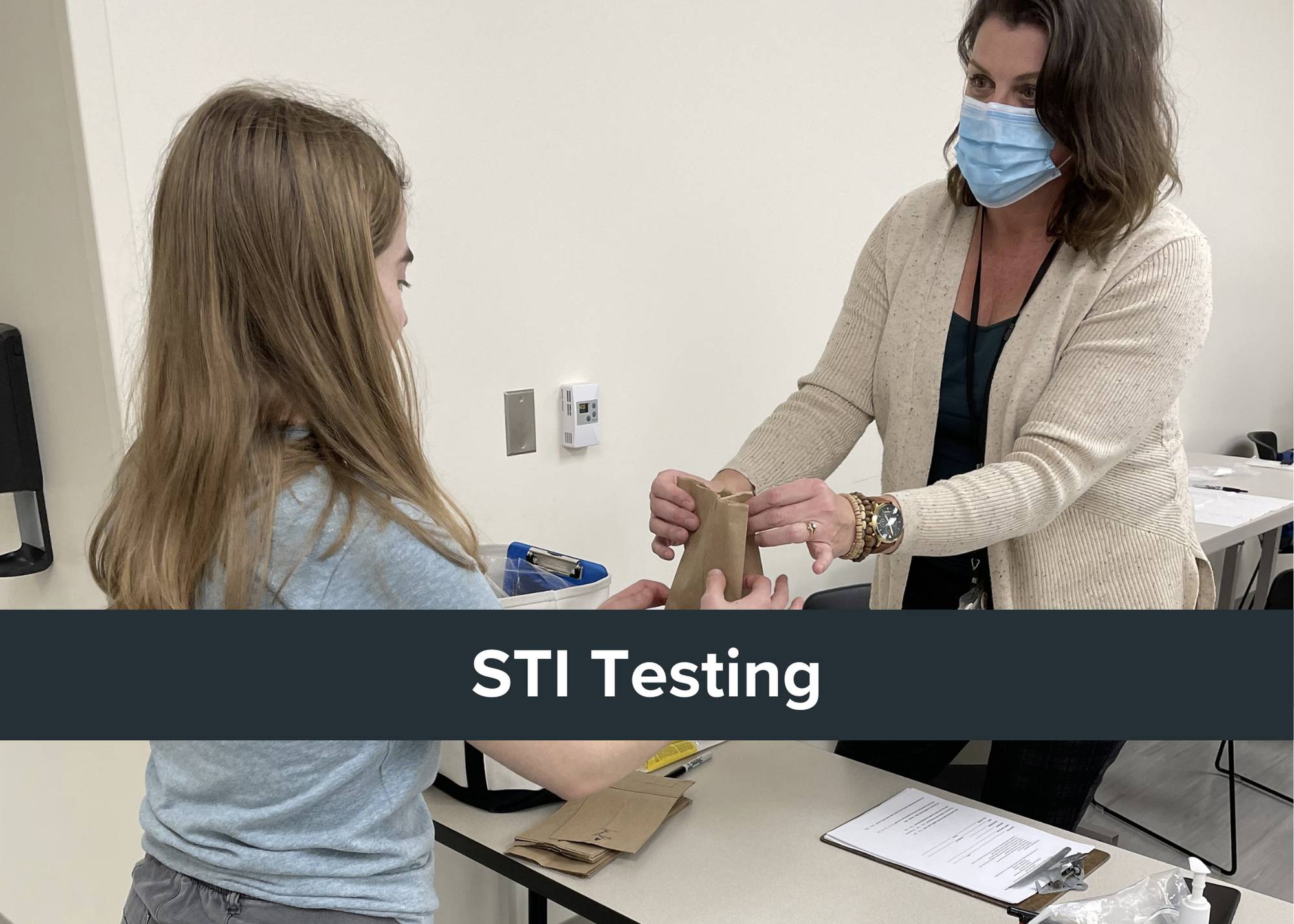 Says "STI testing" with photo of someone taking paper bag from health care provider